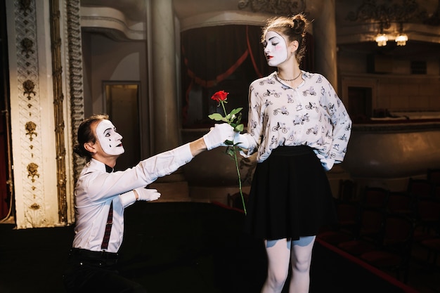 Free Photo male mime giving red rose to female mime artist on stage