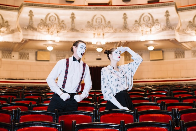 Male mime looking at female mime looking up in auditorium