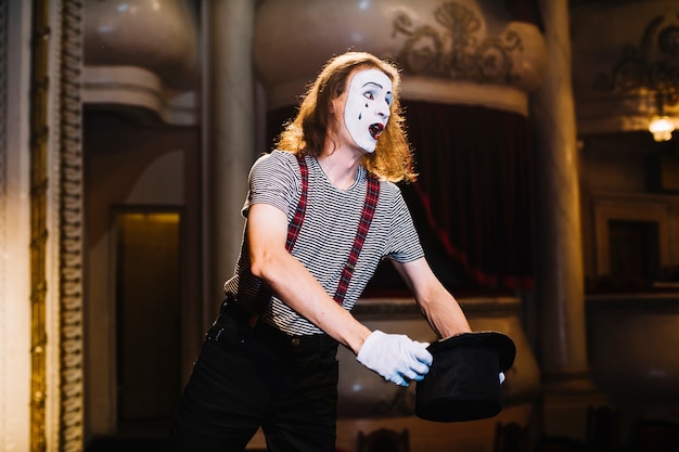 Free photo male mime performing on stage holding hat