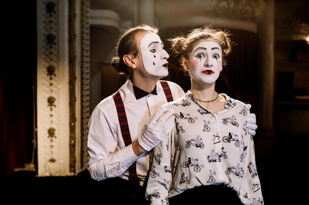 Male mime standing behind the surprised female mime