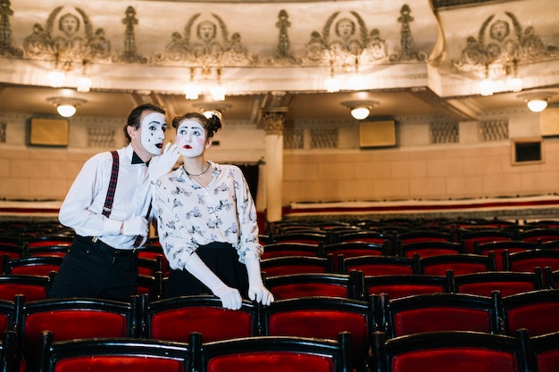 Free Photo male mime whispering in female mime's ear in the auditorium