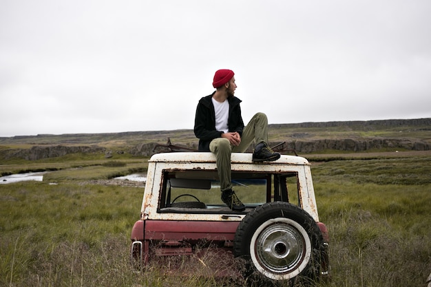 Free Photo male model in cool outfit on top of car in junk yard