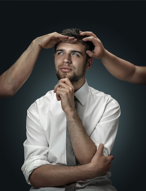 Free Photo male model surrounded by hands like his own thoughts on dark background.