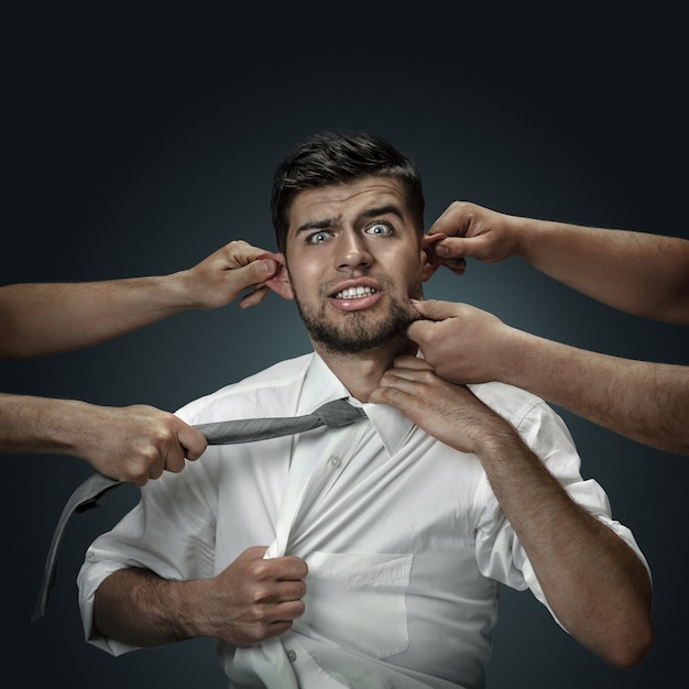 Free Photo a male model surrounded by hands like his own thoughts on dark wall