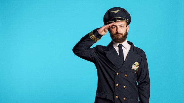 Free Photo male model wearing pilot uniform and hat on camera, having professional occupation at airline. young man working as captain and flying plane, being happy and positive in studio.