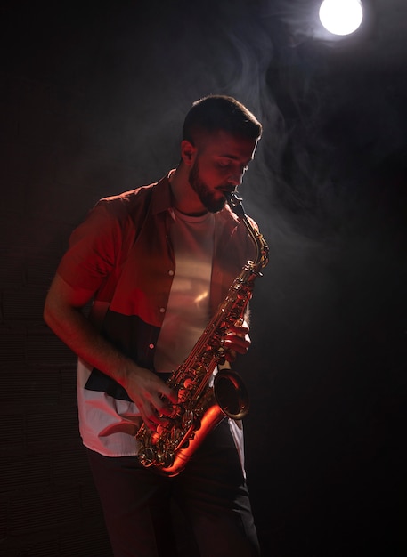 Free photo male musician playing the saxophone in spotlight