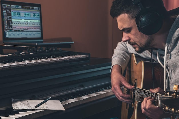 Free Photo male musician plays the guitar at home in the workplace near the computer