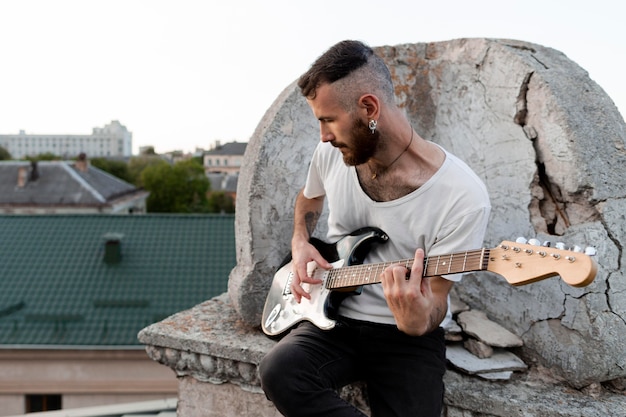 Free photo male musician on roof top playing electric guitar