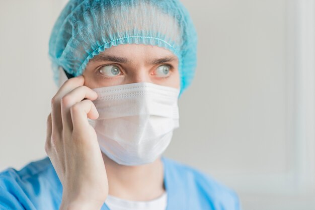 Male nurse with mask talking over phone