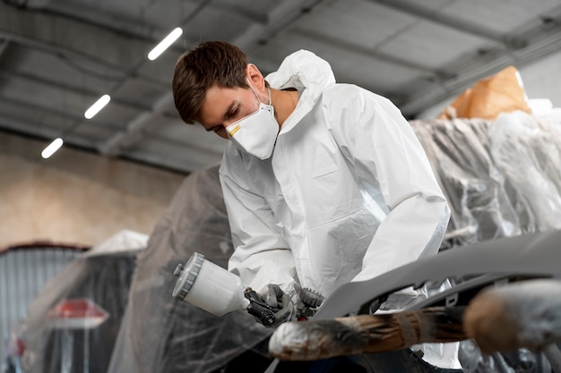 Free photo male painter dressed in hazmat suit inside car shop