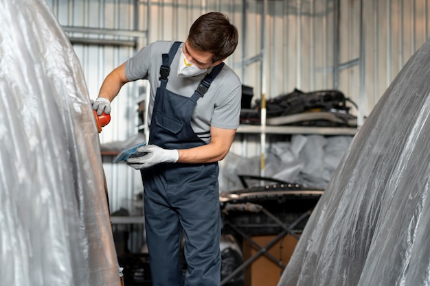 Free Photo male painter in overalls doing his work at the car shop