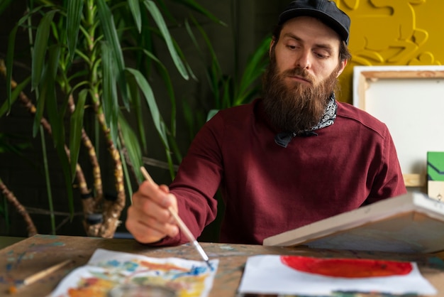 Free photo male painter in the studio using watercolor on his art