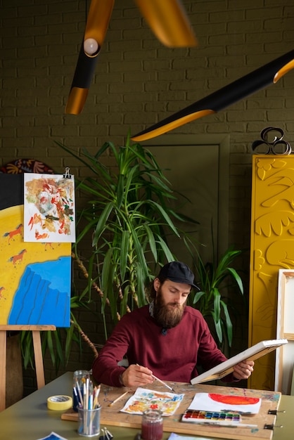 Free Photo male painter in the studio using watercolor on his art