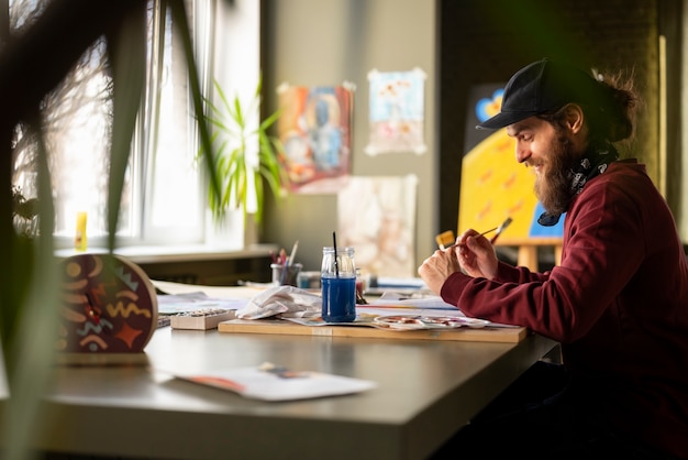 Free Photo male painter in the studio using watercolor on his art