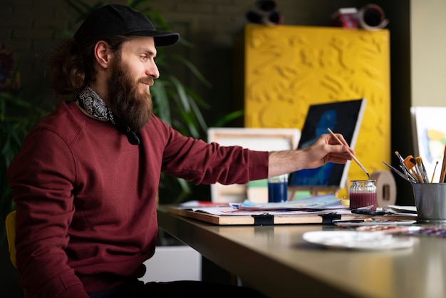 Free Photo male painter using watercolor on his art in the studio