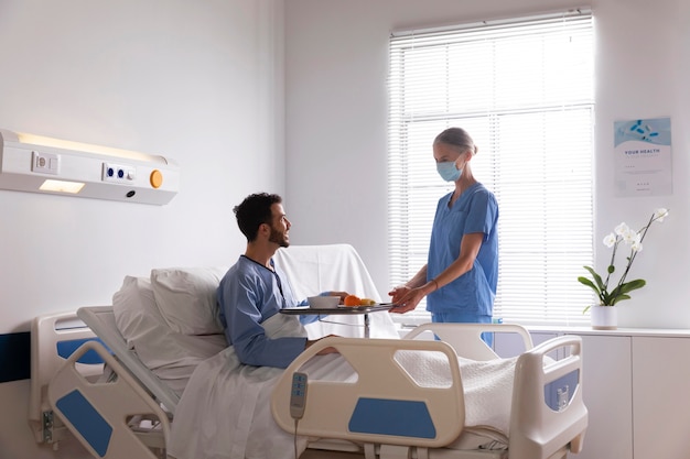 Male patient in bed talking to a nurse