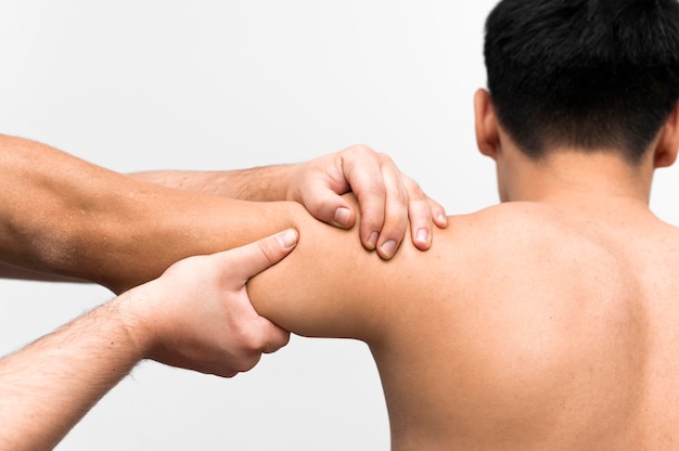 Male patient getting shoulder massage from physiotherapist