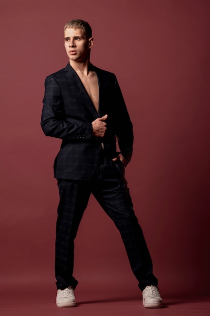 Male performer posing elegantly in sneakers and suit without shirt