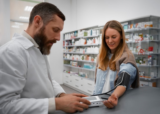 Free photo male pharmacist checking woman's blood pressure