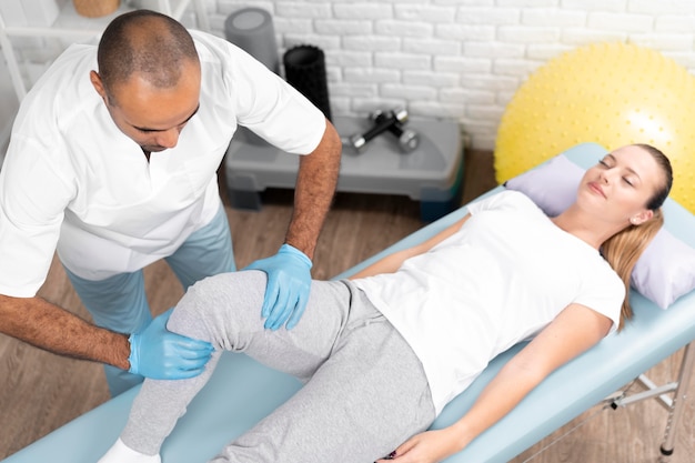 Male physiotherapist checking woman's knee