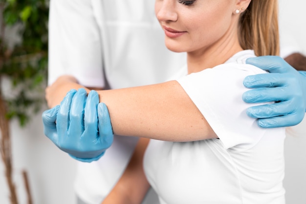 Male physiotherapist checking woman's shoulder flexibility