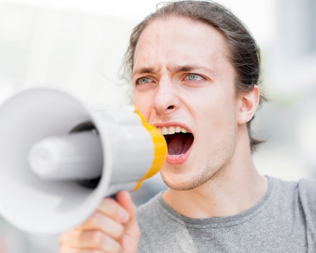 Free photo male protester screaming in megaphone close-up