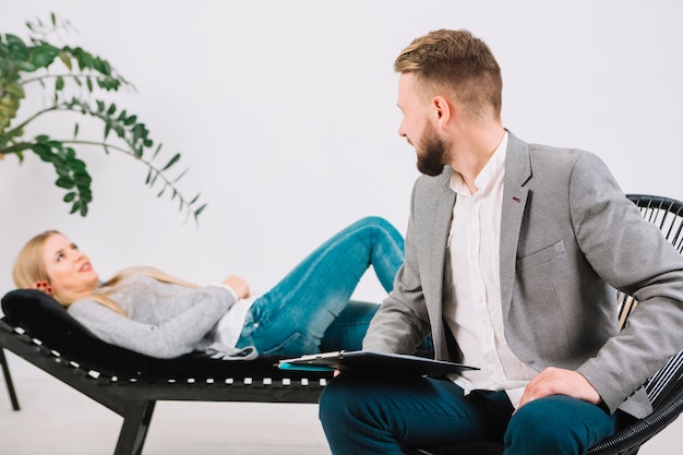 Free photo male psychologist looking at her female patient lying on couch