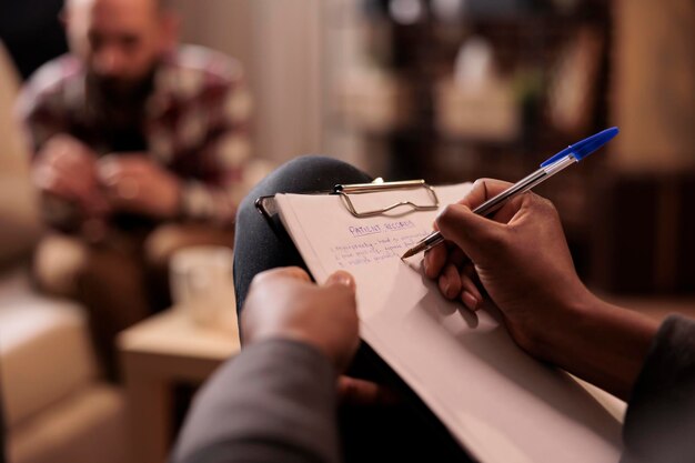 Male psychologist taking notes at couple therapy session to help with relationship issues, counselor giving advice. Explaining marriage problems, using paper to do psychoanalysis. Close up,