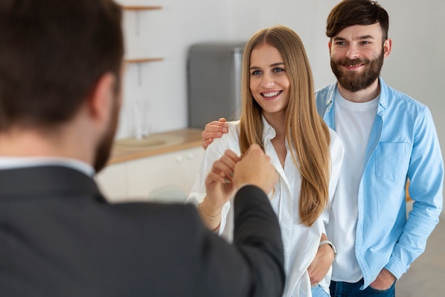 Free photo male real estate agent doing business and showing house to potential buying couple