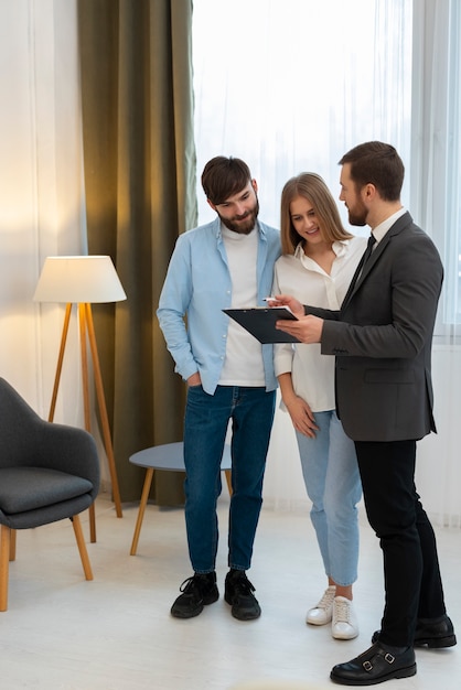 Male real estate agent doing business and showing house to potential buying couple