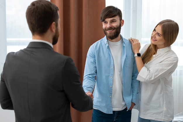 Male real estate agent doing business and showing house to potential buying couple