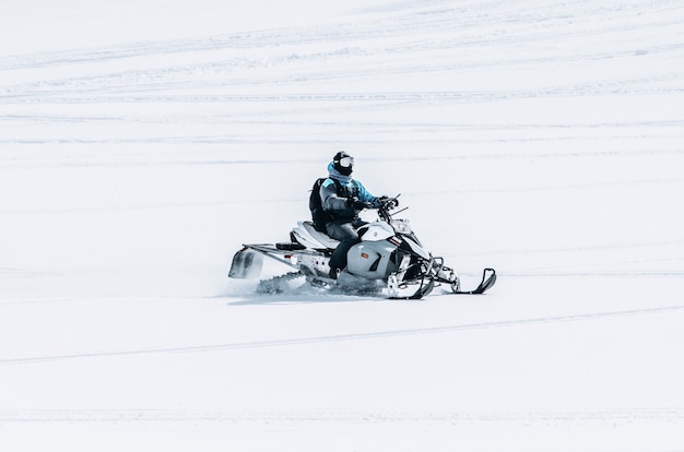 Free photo male riding a snowmobile in a large snowy field