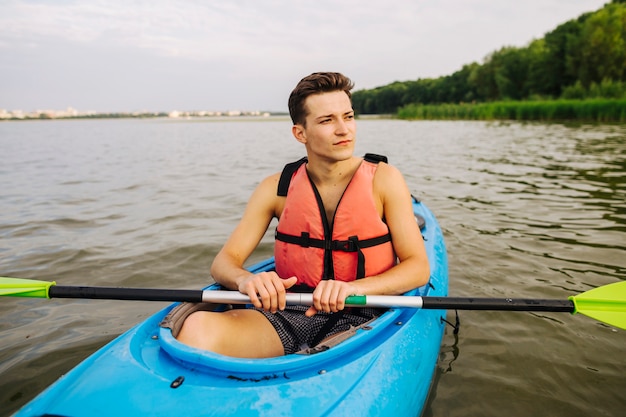 Male sitting in kayak holding paddle looking away