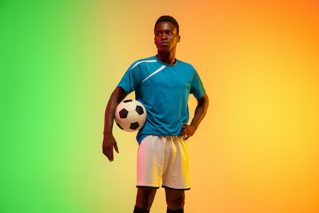 Male soccer, football player training in action isolated on gradient studio in neon light