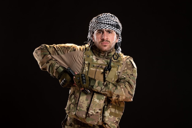 Free photo male soldier in camouflage fighting with gun on black wall