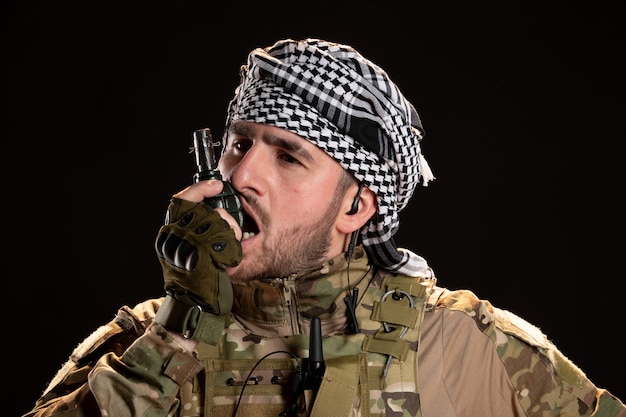 Free photo male soldier in camouflage holding grenade on a black wall