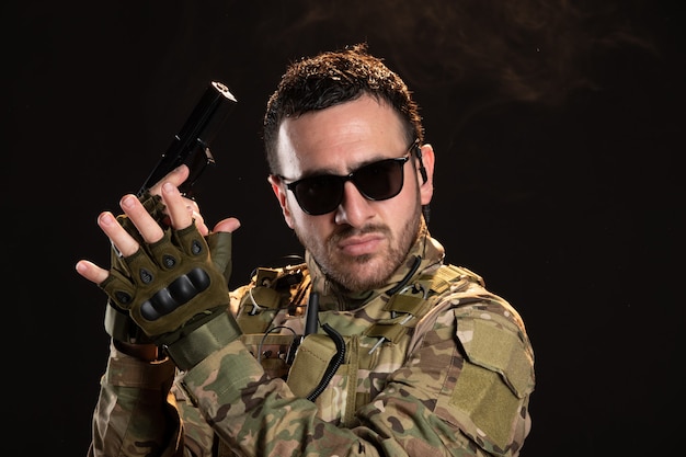 Free Photo male soldier in camouflage holding gun on dark wall