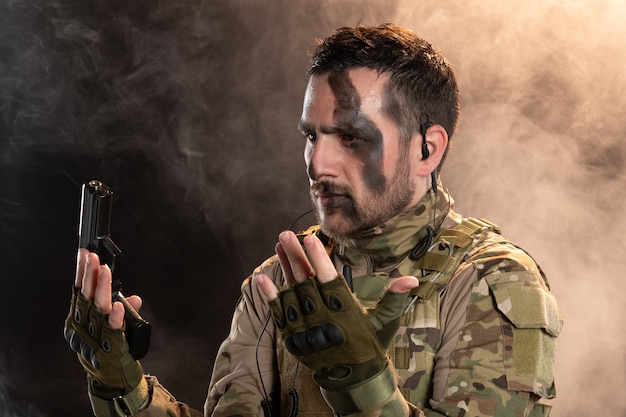 Free Photo male soldier in camouflage surrending on a smoky dark wall 