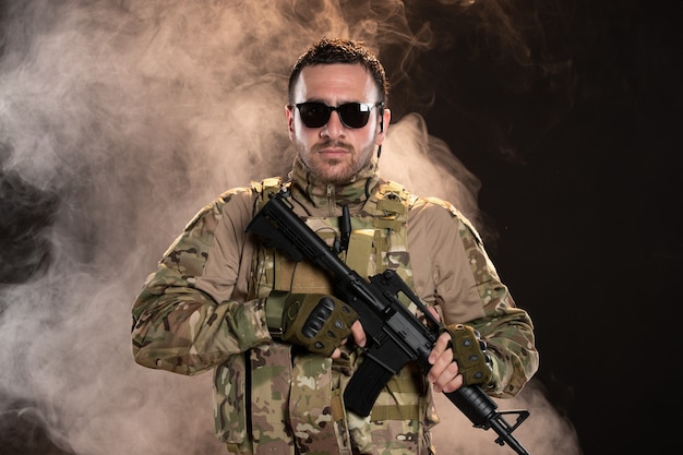 Male soldier in camouflage with machine gun on dark smoky floor warrior tank military