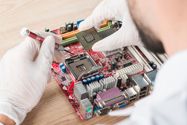 Free photo male technician inserting chip in computer motherboard on wooden desk