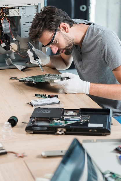 Free photo male technician repairing computer motherboard on wooden desk