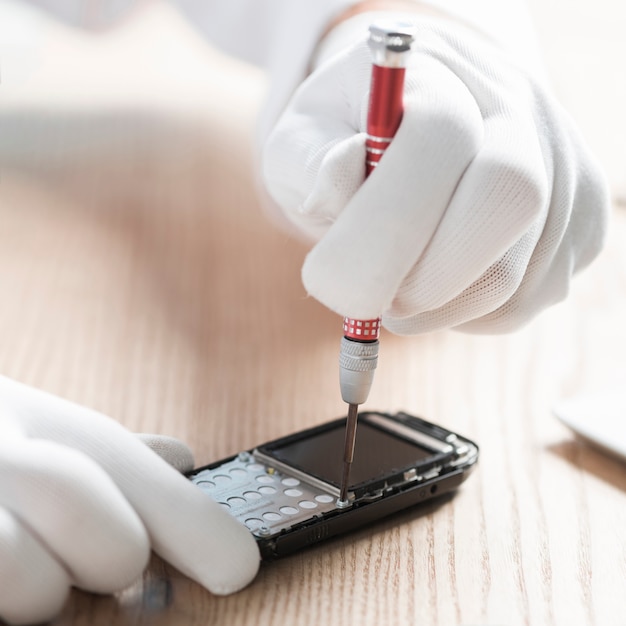 Free photo male technician wearing gloves repairing cellphone