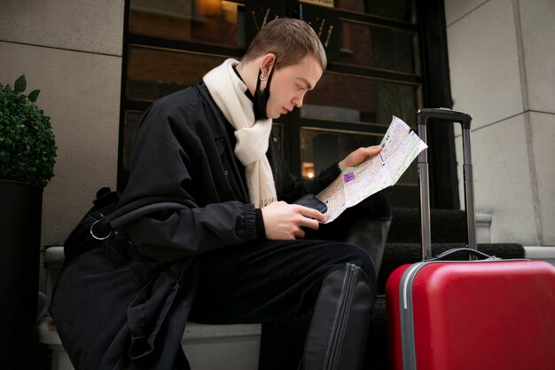 Male tourist checking map next to suitcase