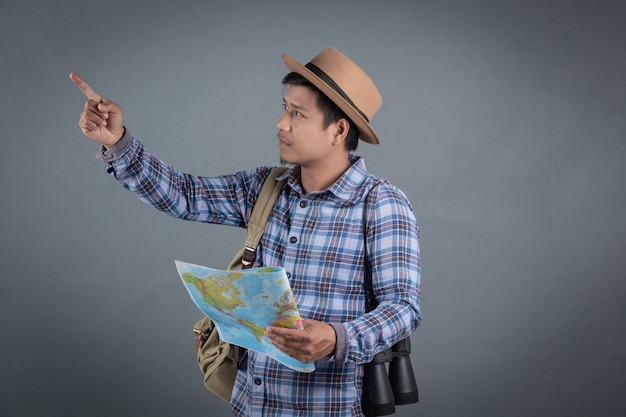 Male tourists carrying backpacks carrying a gray background map.