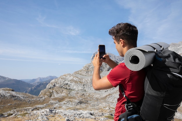 Male traveler hiking on mountains while having his essentials in a backpack