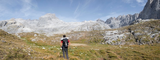 Male traveler hiking on mountains while having his essentials in a backpack