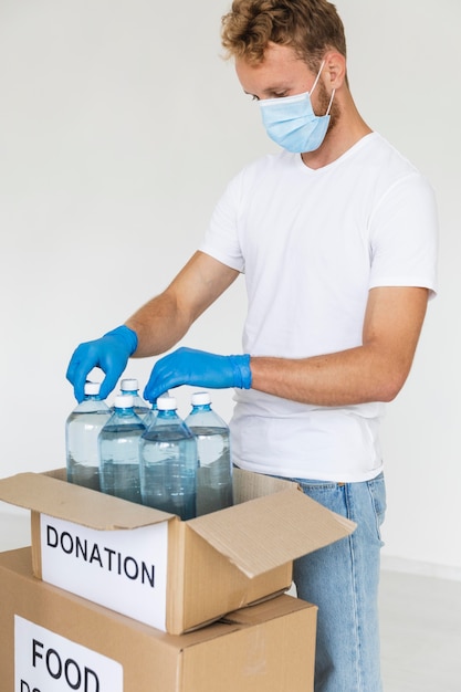 Free photo male volunteer preparing water bottles for donation