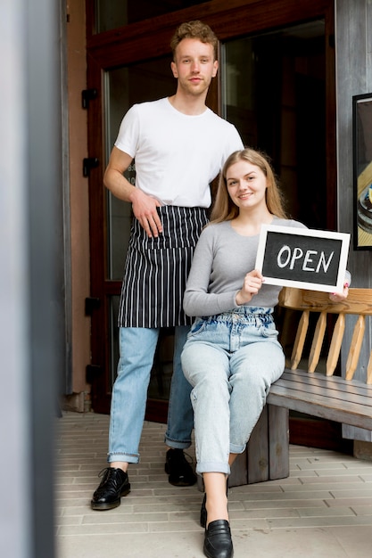 Free photo male waiter and woman with open sign for coffee shop