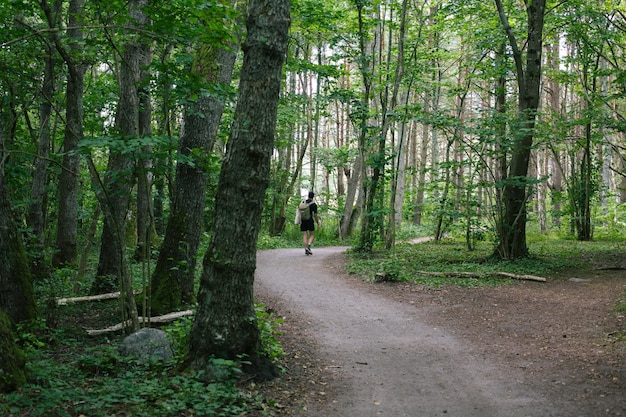 Male with a backpack walking on a pathway in the middle of the forest