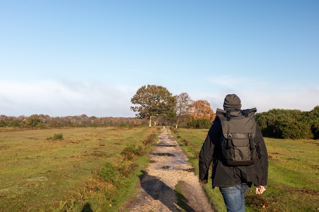 Male with a backpack walking through a pathway in a field